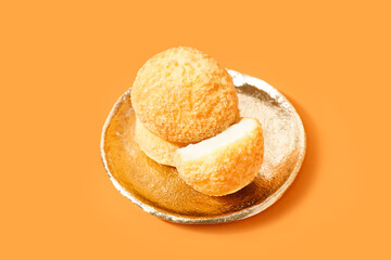 Plate with delicious choux pastry on orange background