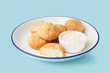 Plate with tasty choux dessert on blue background