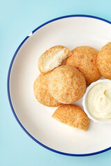 Plate with tasty choux dessert on blue background, closeup