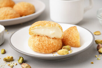 Plate with tasty choux dessert on light background
