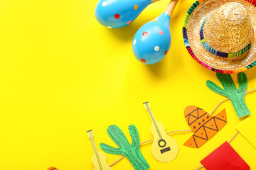 Fototapeta na wymiar Mexican maracas with sombrero hat and paper garland on yellow background, closeup