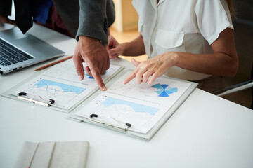 Fototapeta na wymiar Hands of business people pointing at chart in report on office desk