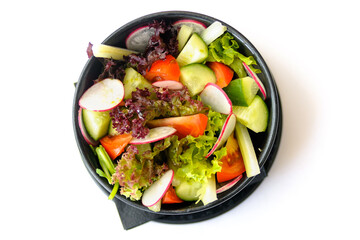 Salad of fresh seasonal vegetables in a black plate isolated