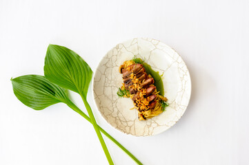 Beef slices on a white plate with a green leaves