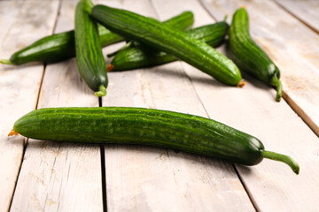 Fresh cucumbers on light wooden background