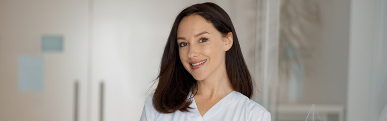 Fototapeta premium Portrait of a smiling nurse standing near the reception in a medical clinic