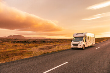 RV Motorhome camper van road trip. People on travel vacation adventure. Tourists in rental car campervan by view of mountains in beautiful nature landscape at sunset. From Iceland - 593848907