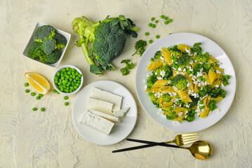 Plate with tasty penne pasta and broccoli on light grunge background