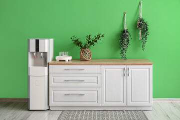 Interior of kitchen with modern water cooler near green wall