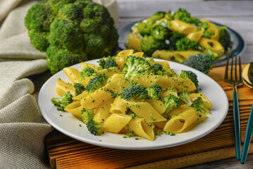 Plate with tasty pasta and broccoli on grey wooden background