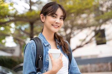 Portrait of young Asian woman student with coffee and backpack outdoor