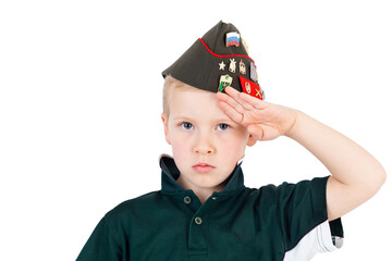 Young caucasian boy saluting playing dressups in green 'army' shirt and russian folding army hat -...