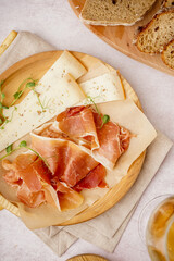 Plate with slices of tasty jamon and cheese on light background, closeup