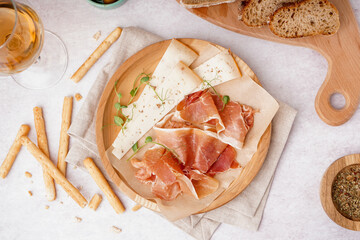 Plate with slices of tasty jamon and cheese on light background