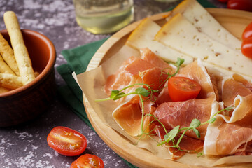 Plate with slices of tasty jamon and cheese on grunge background, closeup