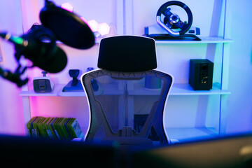 Darkroom for a professional gamer with a comfortable empty gamer chair, computer table, neon...