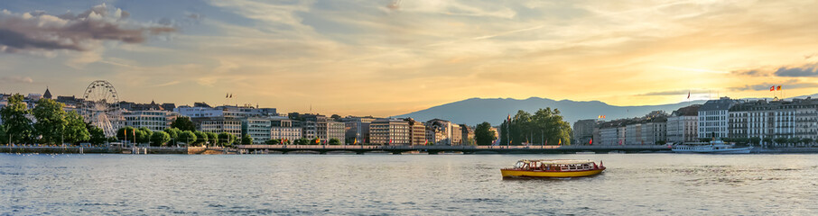 Panoramic skyline view of Geneva city at sunset - Yellow tour boat on Lake Geneva in Switzerland.