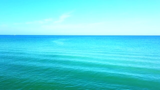 Look at this perfect blue waves in Florida ocean, bright blue background, cinematic shot.