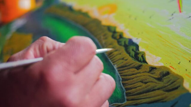 Close up shot of a painter's hand drawing art on a canvas. artists