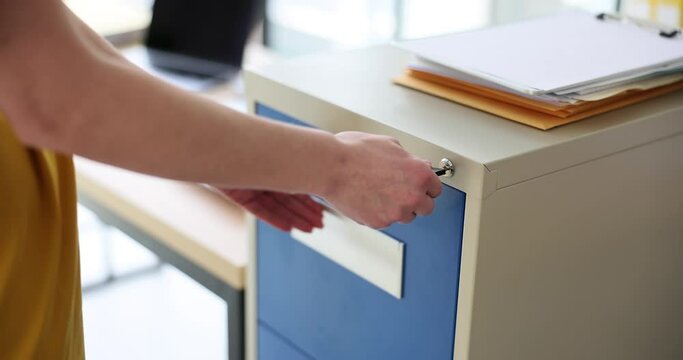 Secretary manager with key opens metal cabinet for storing securities and documents. Storage of important financial documents