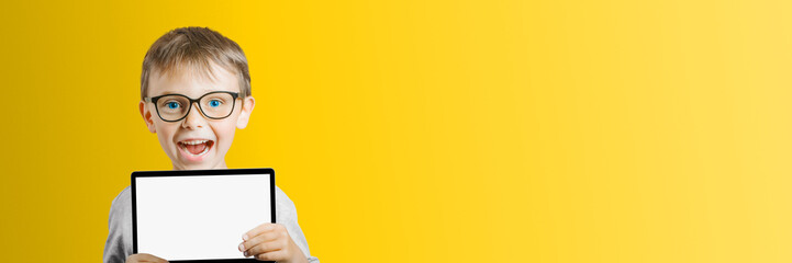 a Happy child boy holding a tablet on color background