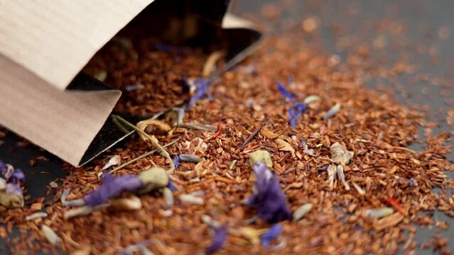Rooibos flower herbal tea scattering with paper pack close up. Rotation. Relax healthy drink