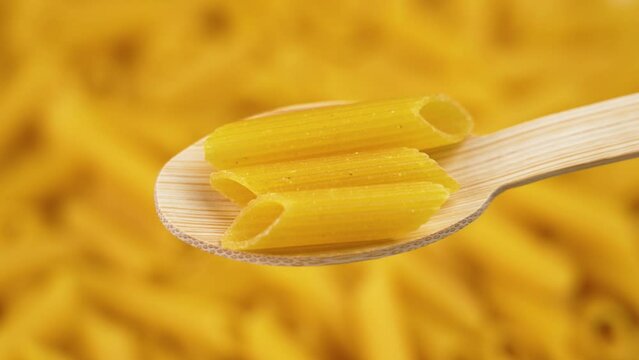 Yellow lentil pasta in a bamboo wooden spoon with rotating background. Macaroni gluten free