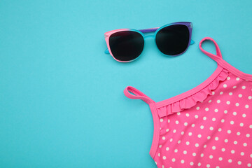 Summer kid's vacation concept - swimsuit with cute sunglasses on blue background. Holiday concept,...