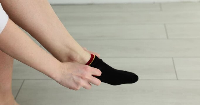 Woman puts on cotton colored socks in morning. Choice of socks by fabric material