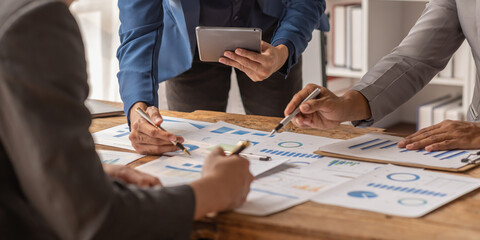 Group of confident business people point to graphs and charts to analyze market data, balance sheet, account, net profit to plan new sales strategies to increase production capacity.	