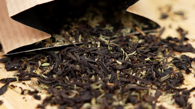 Scattered packaged black herbal tea with thyme with a paper pack close up. Rotation