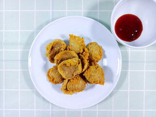 Top view of tahu walik on a white plate. Overhead shot of inside out tofu on a plate. Flat lay shot of tahu walik served with spicy sauce. Originated from Banyuwangi, East Java, Indonesia. Fried tofu.