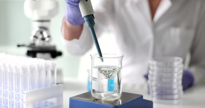 Magnetic stirrer with thermostat sensor scientist takes water samples. Study of composition of liquids experiments in lab