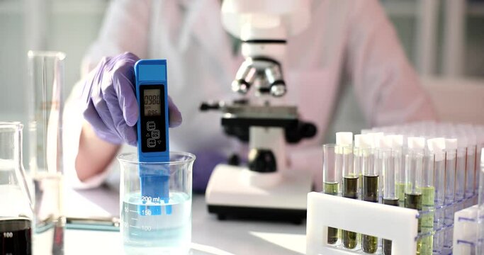 Measuring hardness of water in flask using TDS meter. Testing quality of water or clear liquid for toxins