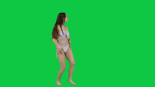 Gorgeous female model in white bikini dancing in front of a green screen