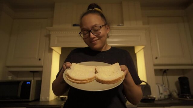 Young woman showing her plate with her soft butter smeared on white bread as snack in the evening.