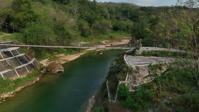 Fast and close pass by Drone over Gantung Wanagama Bridge. Cable bridge. Oyo River in Gunung Kidul on overcast day. Tropical forest.