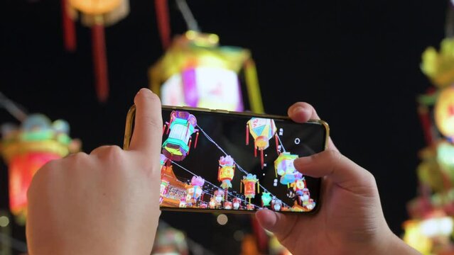 A visitor takes photos of Chinese lanterns with a smartphone during the Mid-Autumn Festival, also called Mooncake Festival.