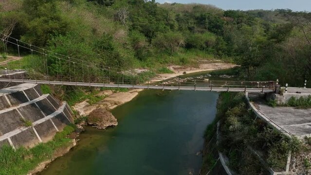 Drone passing along sections of the River Oyo near Gantung Wanagama Bridge (Jemabatan Gantung Wanagama) start of dry season - with matching foliage. Passing over or near to the bridge. Lower