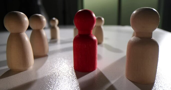 Red wooden figurine of person in crowd of figurines. Individual leader and successful career