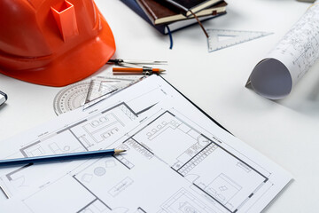 Housing project blueprints  with hardhat and tools on office workplace