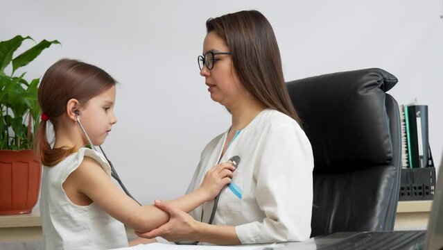 Cute child girl holding stethoscope listening to doctor patient