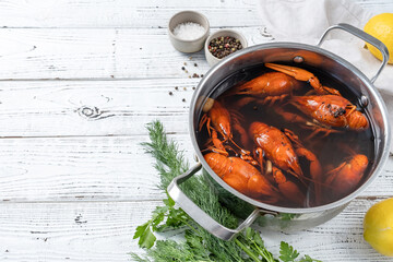 cooked crawfish in saucepan with lemons and spices on wooden background