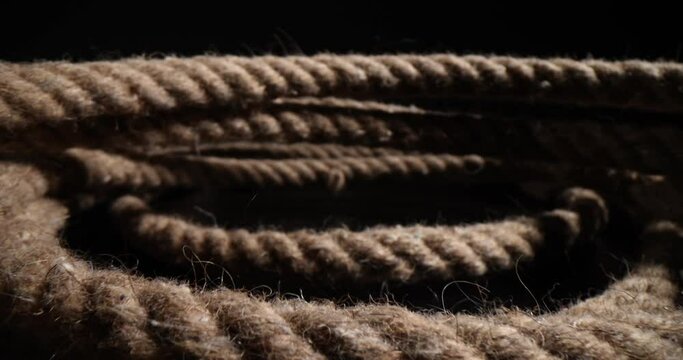 Closeup of nautical rope coiled into spiral on black background. Braided thick rope tied into a skein