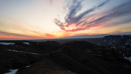 Charyn Grand Canyon with orange rock walls. Aerial view from the drone of the steep canyon walls, cracks and tunnels. There is snow in places. Beautiful sunset and sunrise. Brother of the Grand Canyon
