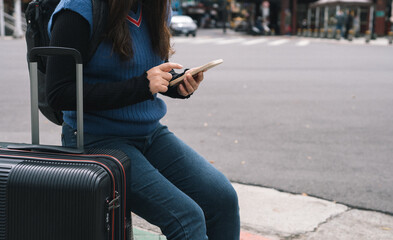 Woman with baggage in downtown city street searching location in map application online on smart phone using GPS navigating.