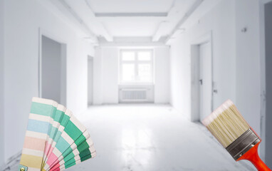 color palette and brush choosing a home wall paint in new home. Home improvements concept.Man and a woman moved into a new house. Selective focus blurred room background, needs renovation copy space