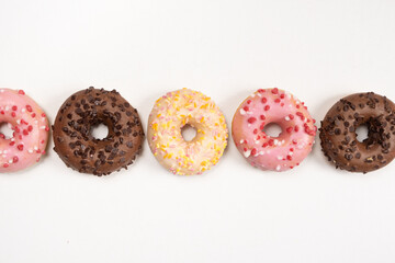 Five donuts in a row - white, pink and chocolate on a white background top view