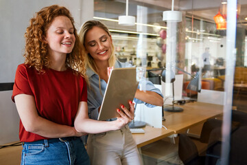 Happy smiling business women working together online on a tablet in office