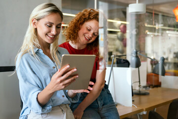 Happy smiling business women working together online on a tablet in office